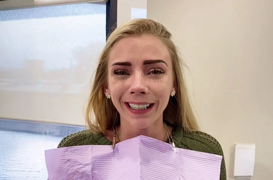 Smiling young woman in the dental chair with a patient bib