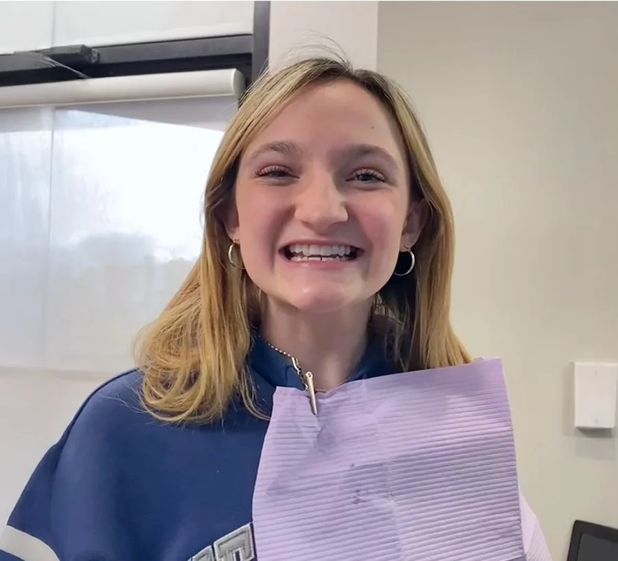 Smiling young woman in the dental chair with a patient bib