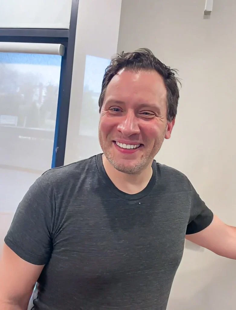 Smiling man in a gray T-shirt in a dental office